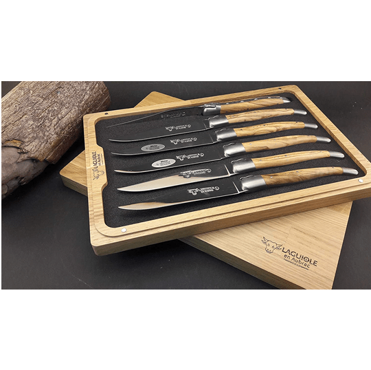 Boxed olive wood set on a dark surface beside a linen cloth