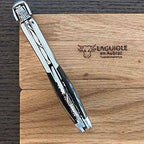 Folded corkscrew laid diagonally on the oak box showing the carved spine