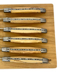 Close view of six carved spines and olive wood handles