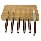Six snakewood steak knives standing upright in front of the box