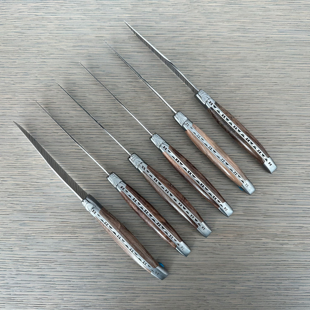 Six grapevine wood steak knives laid in a diagonal row