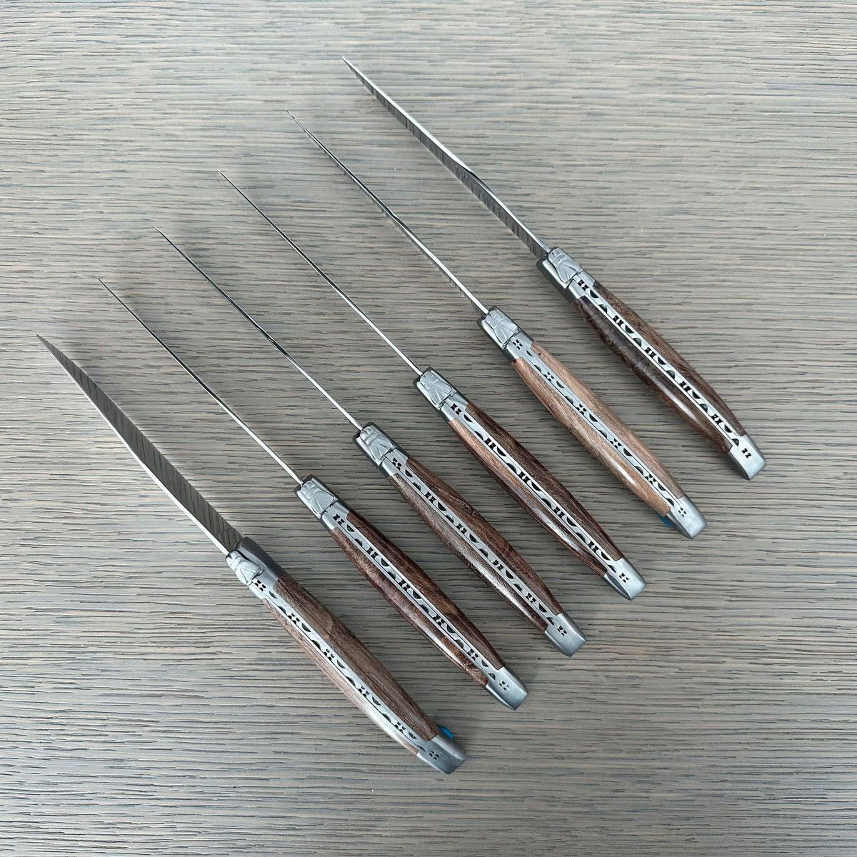 Six grapevine wood steak knives laid in a diagonal row