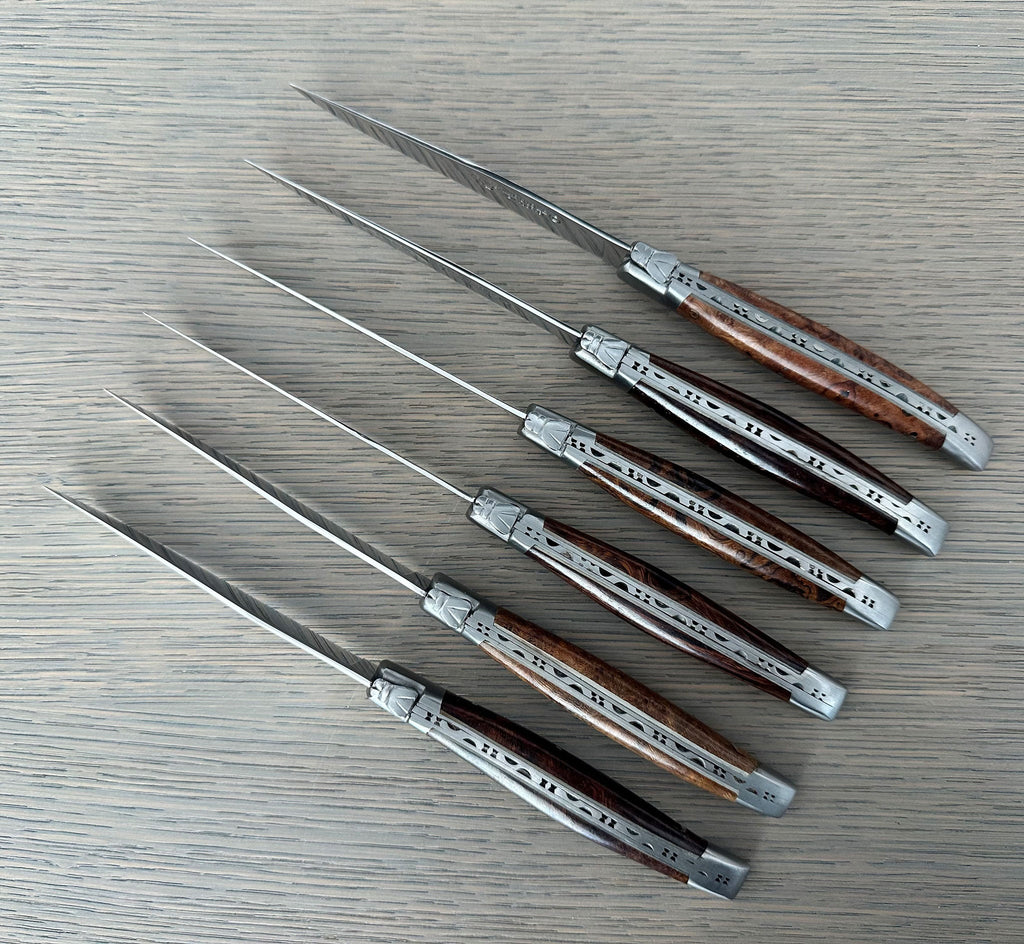 Six ironwood steak knives laid diagonally on a grey surface