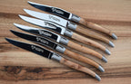Six juniper steak knives fanned on a walnut board