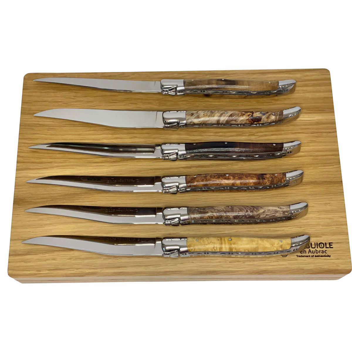Six knives laid on the box lid showing the range of burl colours