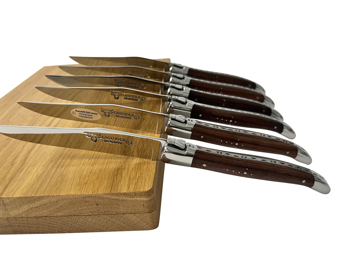 Six rosewood steak knives fanned along the edge of the box