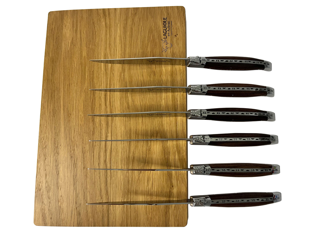 Six knives laid across the wooden box lid