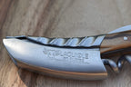 Close view of the engraved blade and twisted bolster on a wood surface