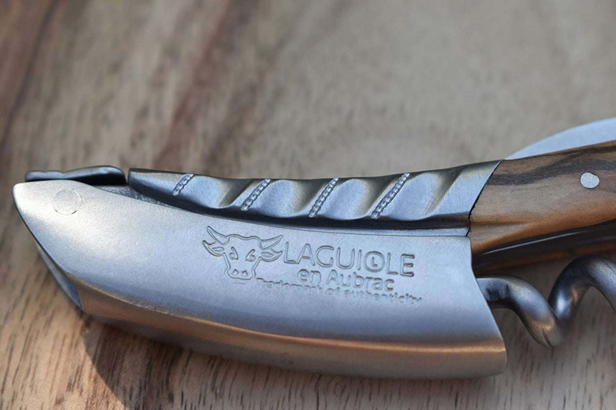 Close view of the engraved blade and twisted bolster on a wood surface