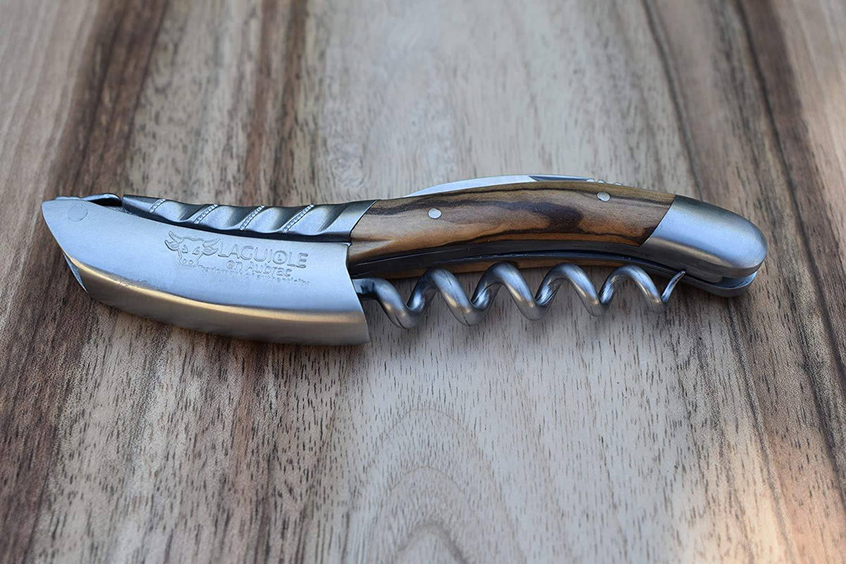Folded olive wood corkscrew lying on a wood surface