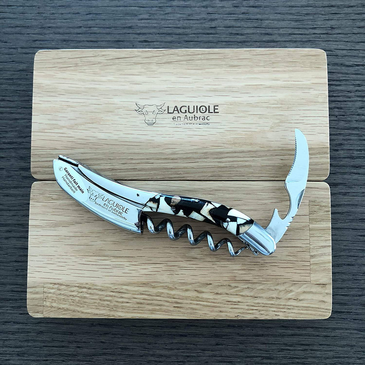 Corkscrew with foil cutter open resting on the Laguiole en Aubrac oak lid