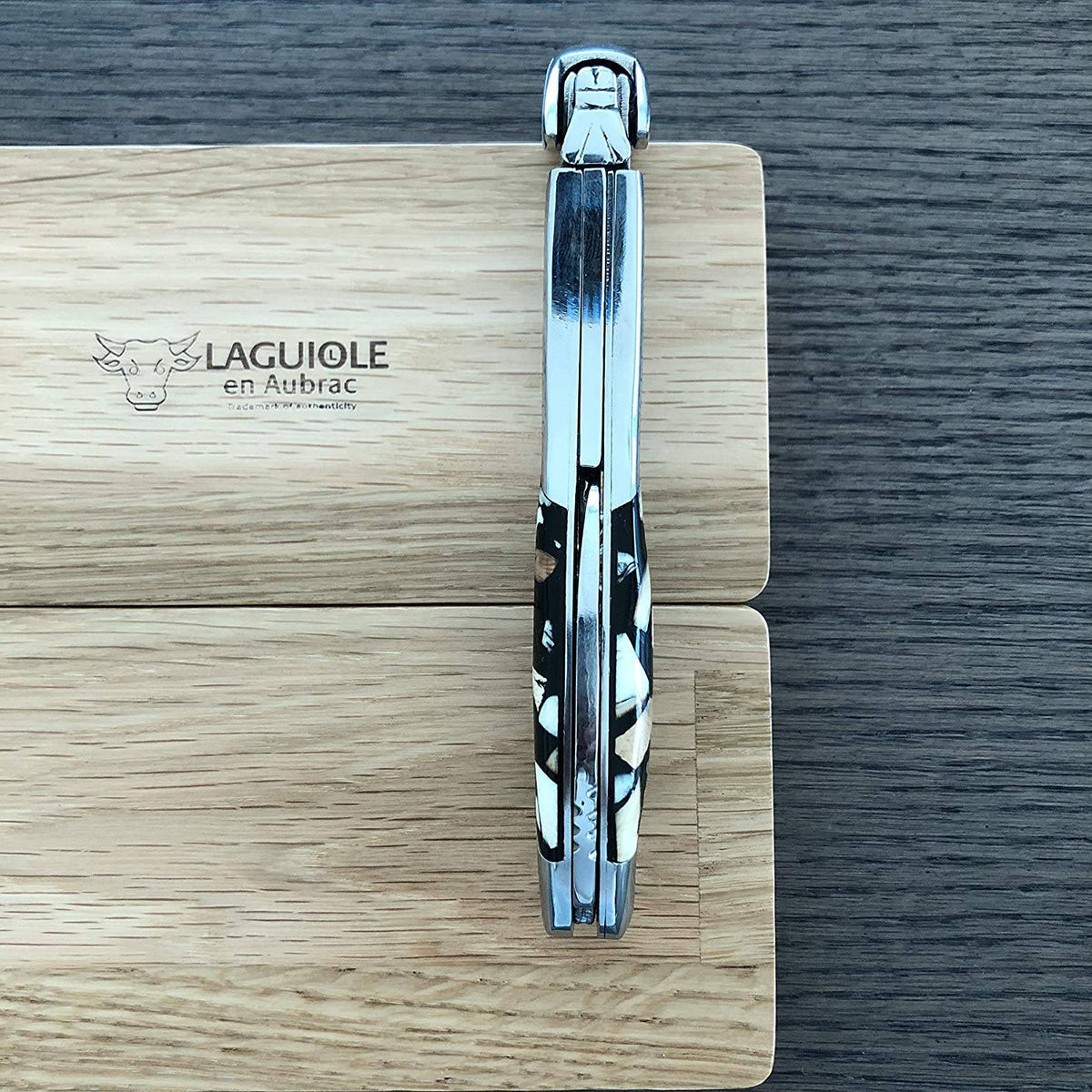 Folded corkscrew standing upright on an engraved oak box