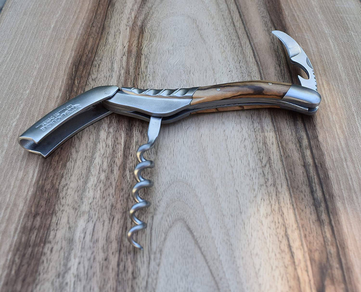 Opened corkscrew with the spiral and foil cutter out on wood