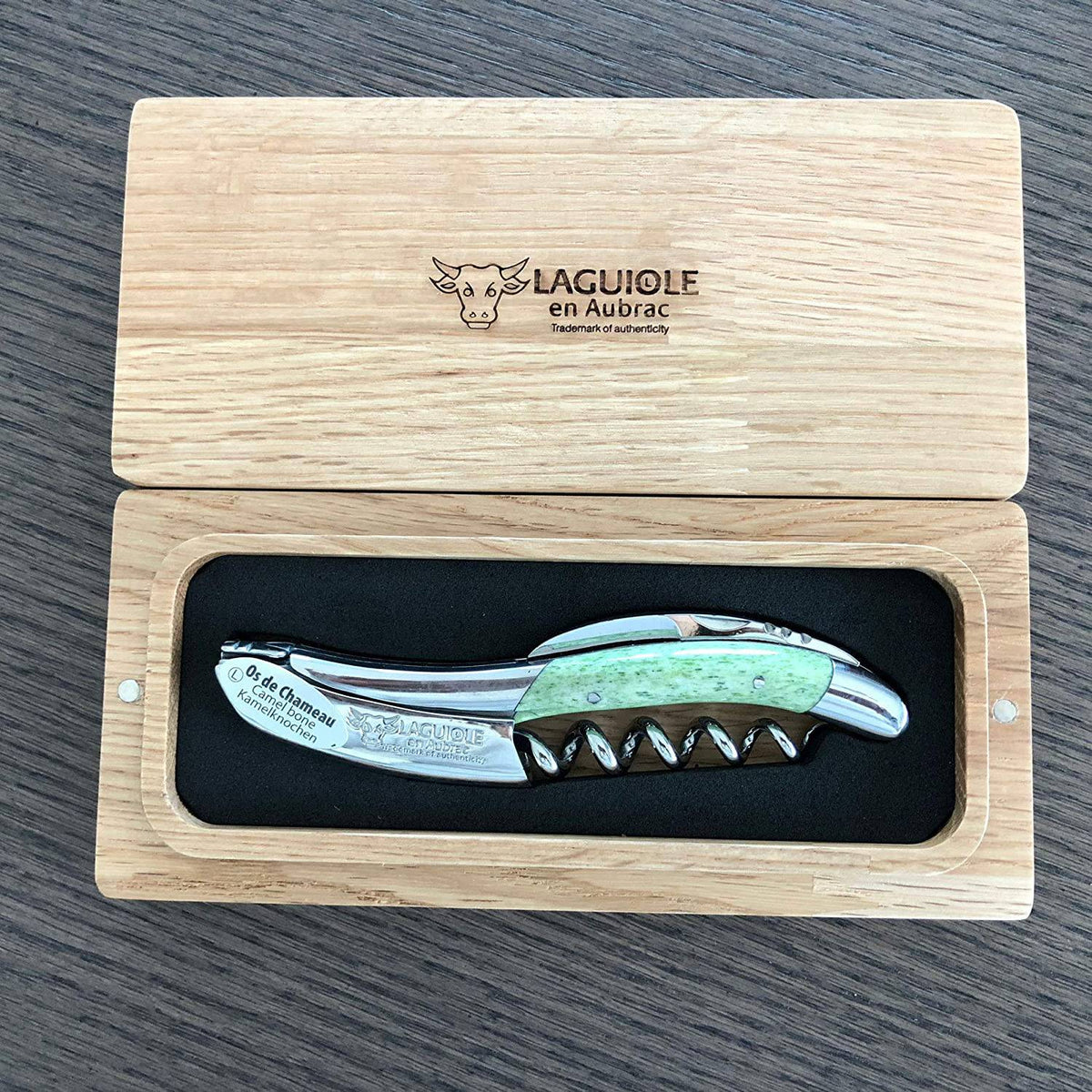 Green handled waiter's corkscrew resting in an open French oak Laguiole en Aubrac box
