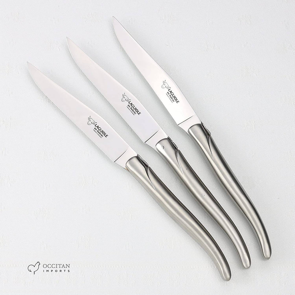Three all-steel steak knives fanned out on a white background