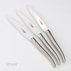 Three all-steel steak knives fanned out on a white background
