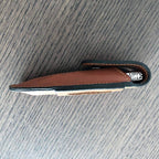 Folding knife tucked inside the brown sheath, seen from the side