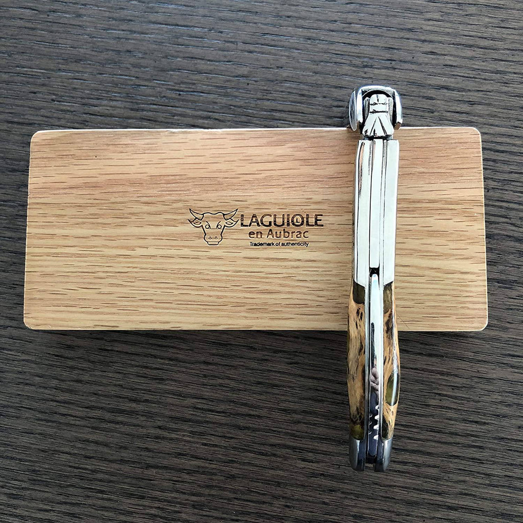 Folded corkscrew standing on edge against the engraved oak box