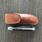 Brown sheath above a closed folding knife on a dark wood surface