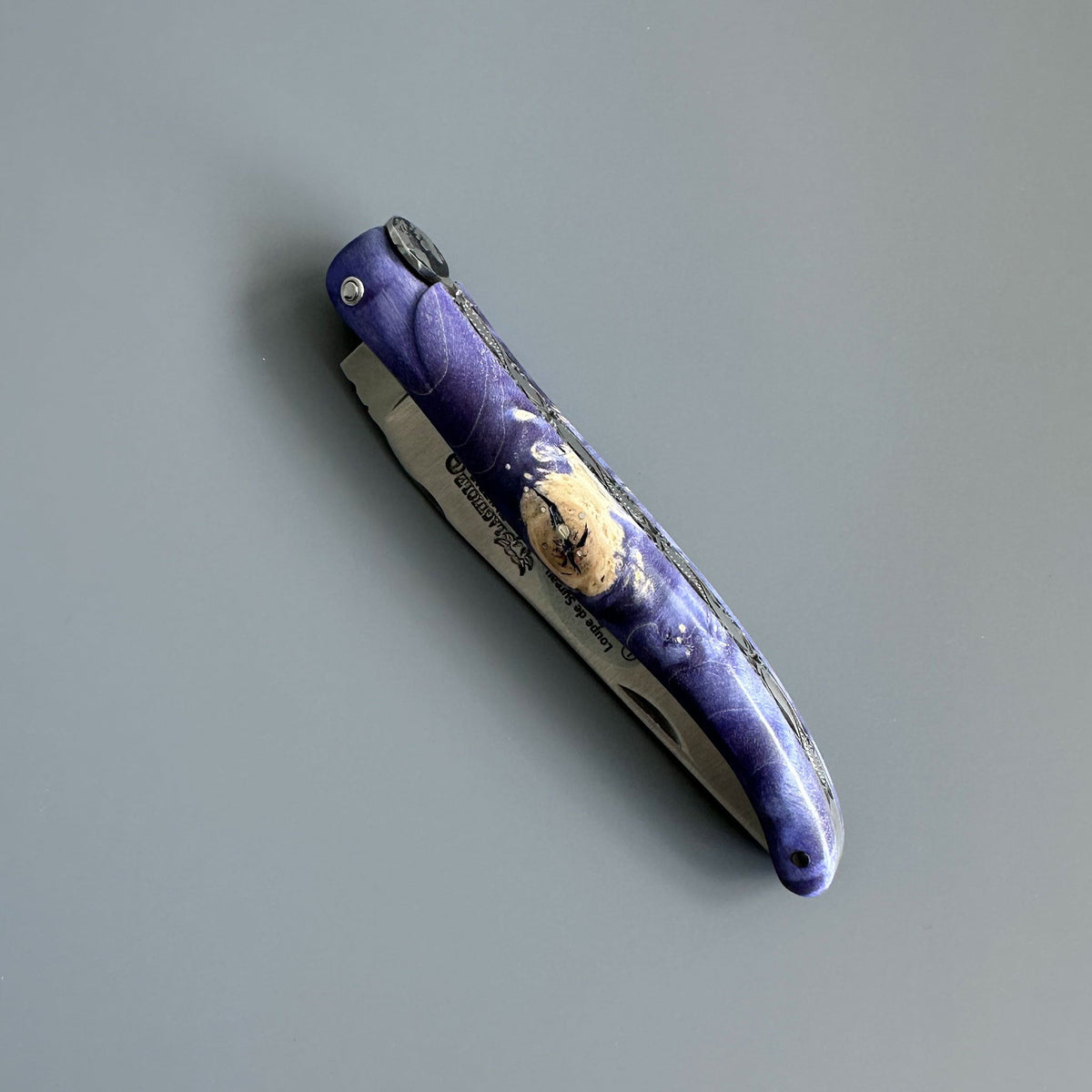 Closed knife showing pale burl flecks in the purple handle