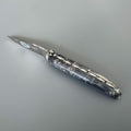 Laguiole Cosmos Earth dark knife with black and grey elder burl handle on grey
