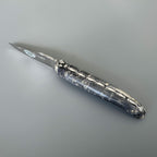 Laguiole Cosmos Earth dark knife with black and grey elder burl handle on grey