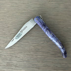 Knife half open on a wood surface with the blade pointing left