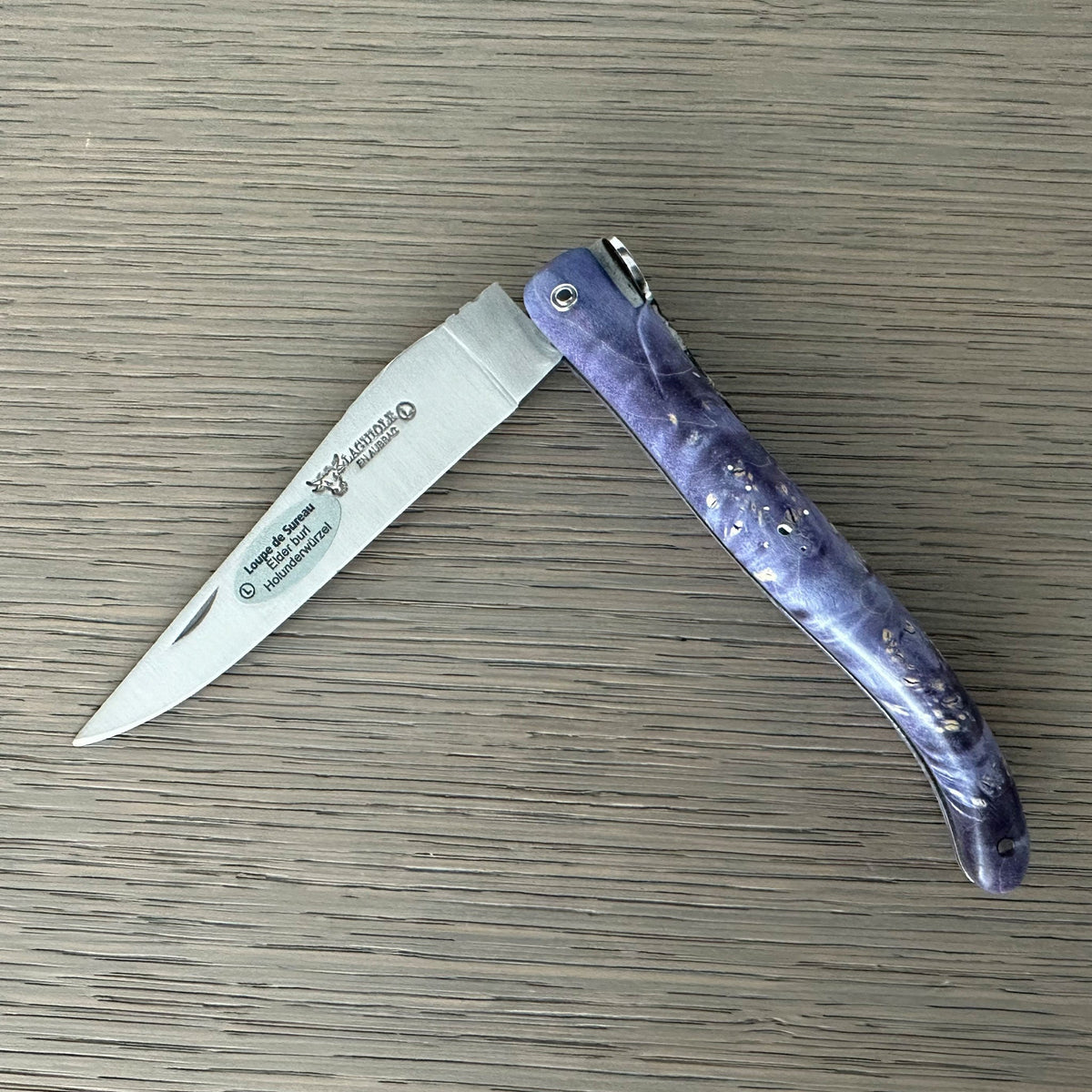 Knife half open on a wood surface with the blade pointing left
