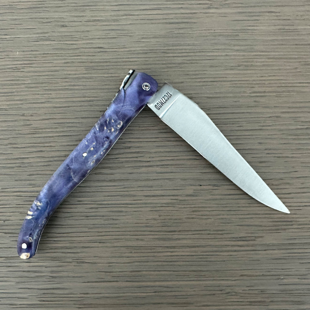 Knife half open on a wood surface with the blade pointing right