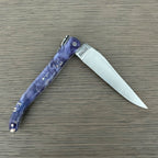 Knife half open on a wood surface with the blade pointing right