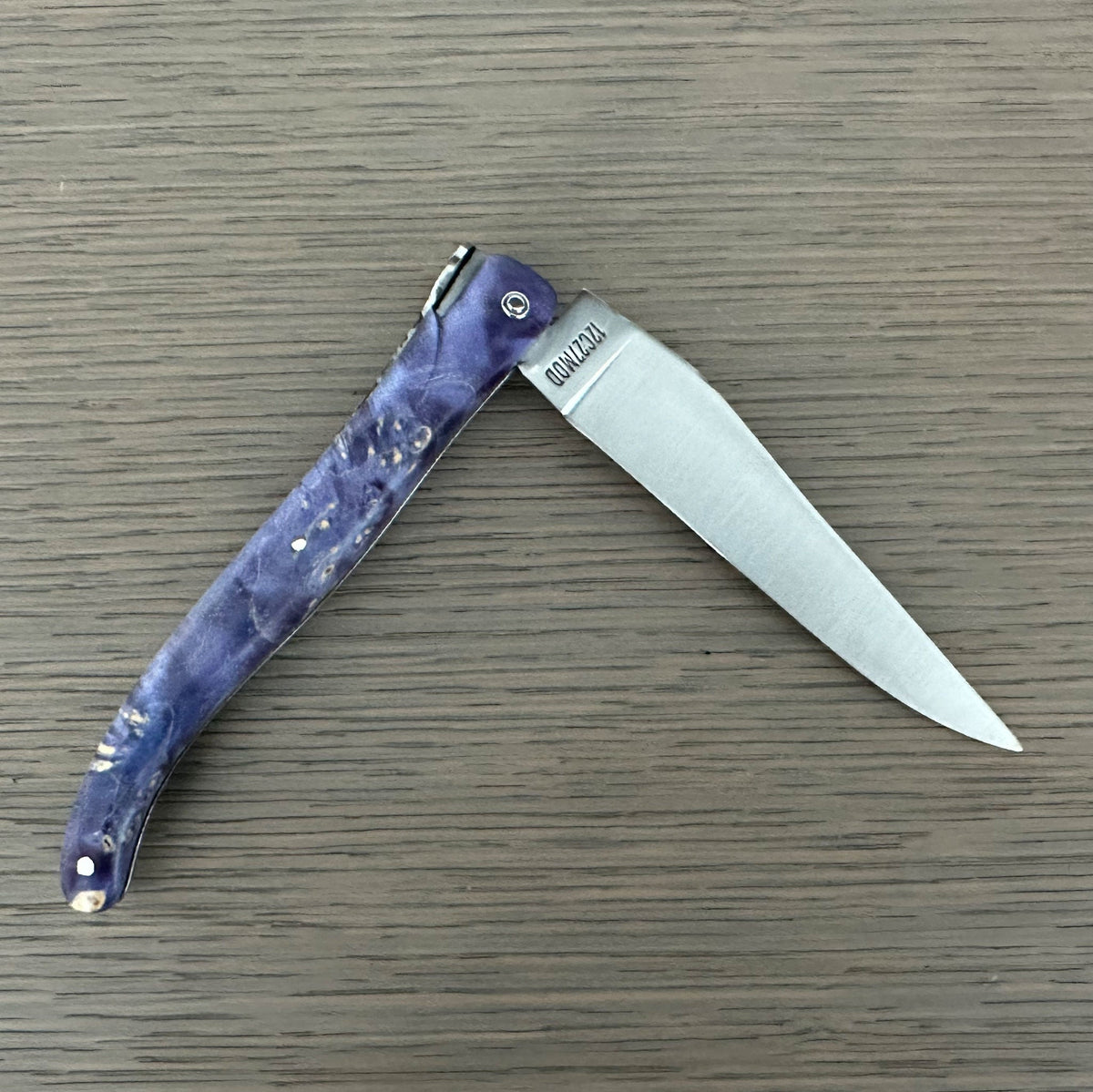 Knife half open on a wood surface with the blade pointing right