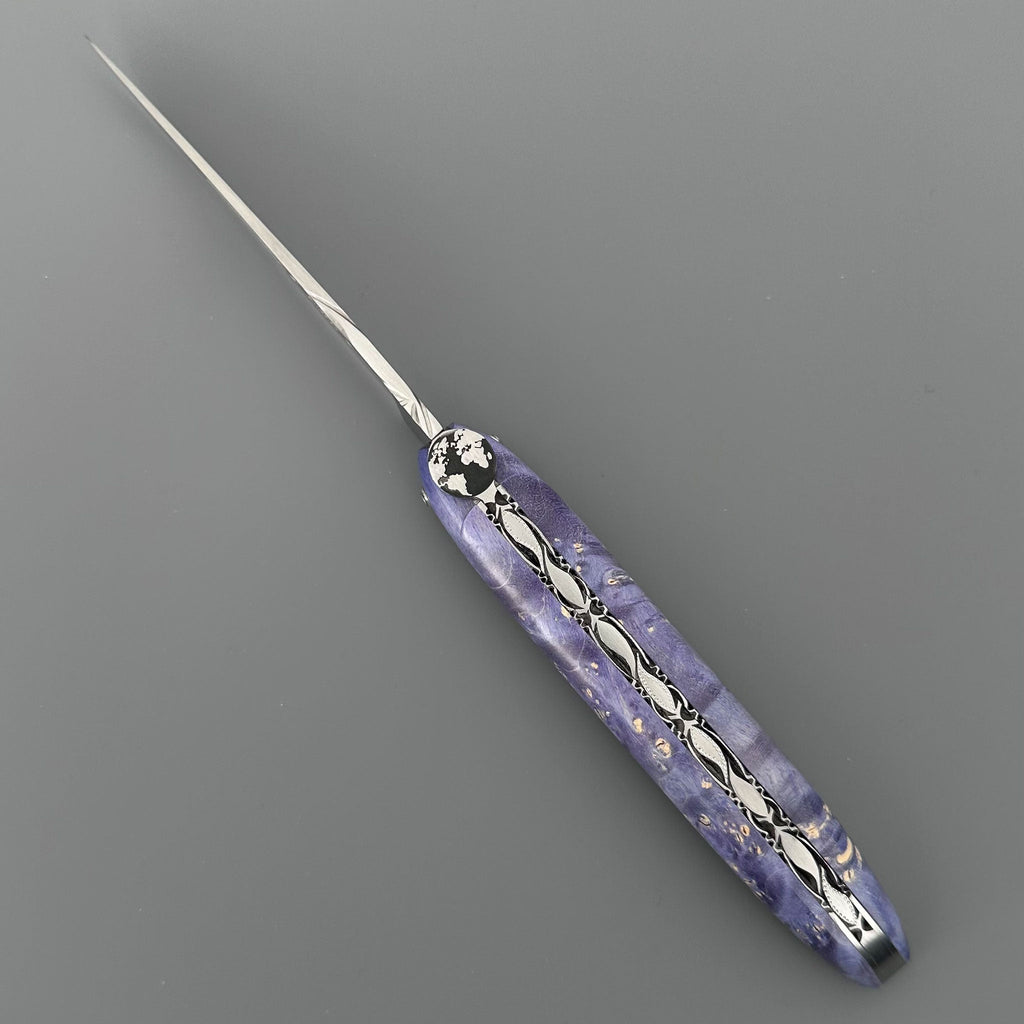 Laguiole Cosmos Earth purple knife with violet elder burl handle, open on grey