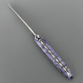 Laguiole Cosmos Earth purple knife with violet elder burl handle, open on grey