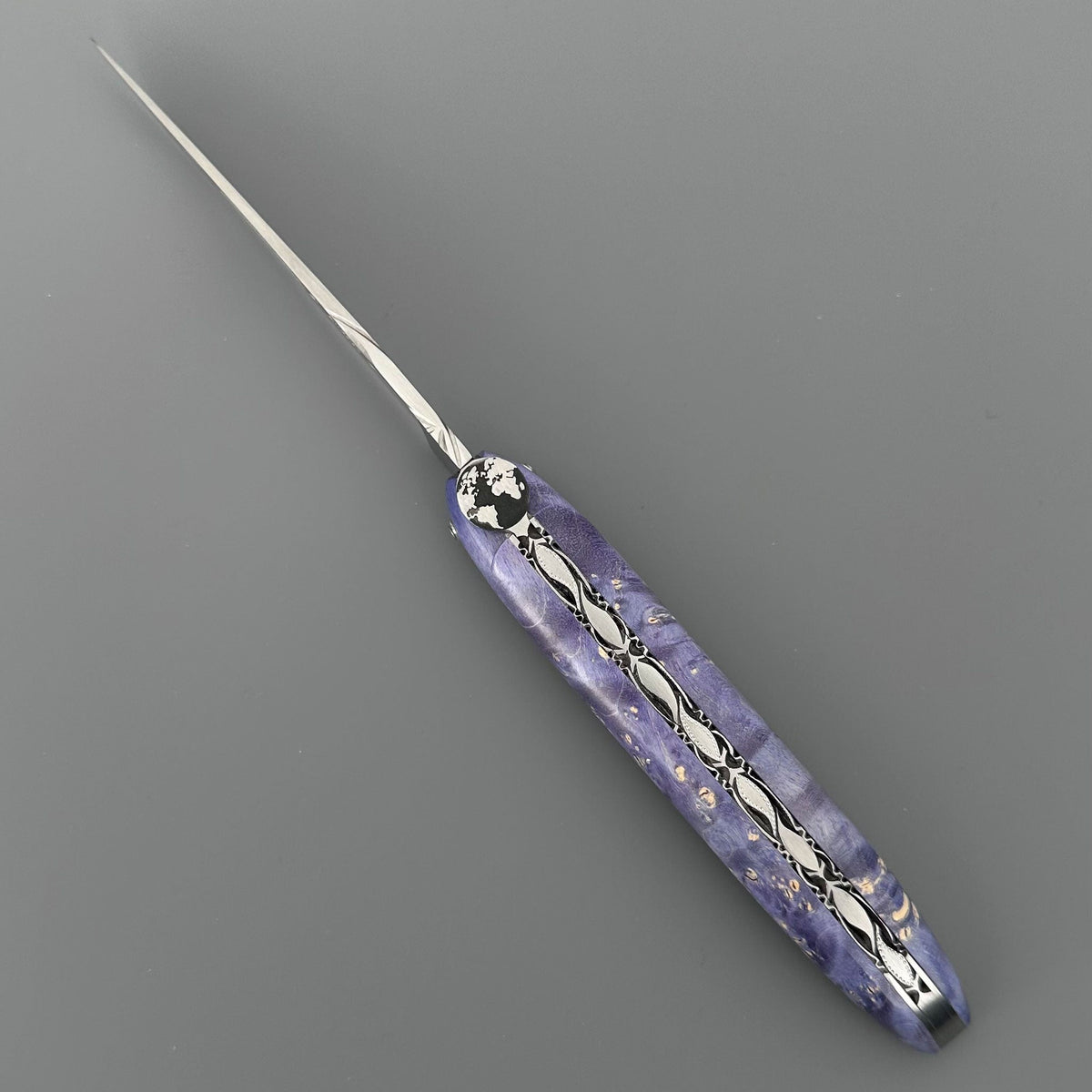 Laguiole Cosmos Earth purple knife with violet elder burl handle, open on grey