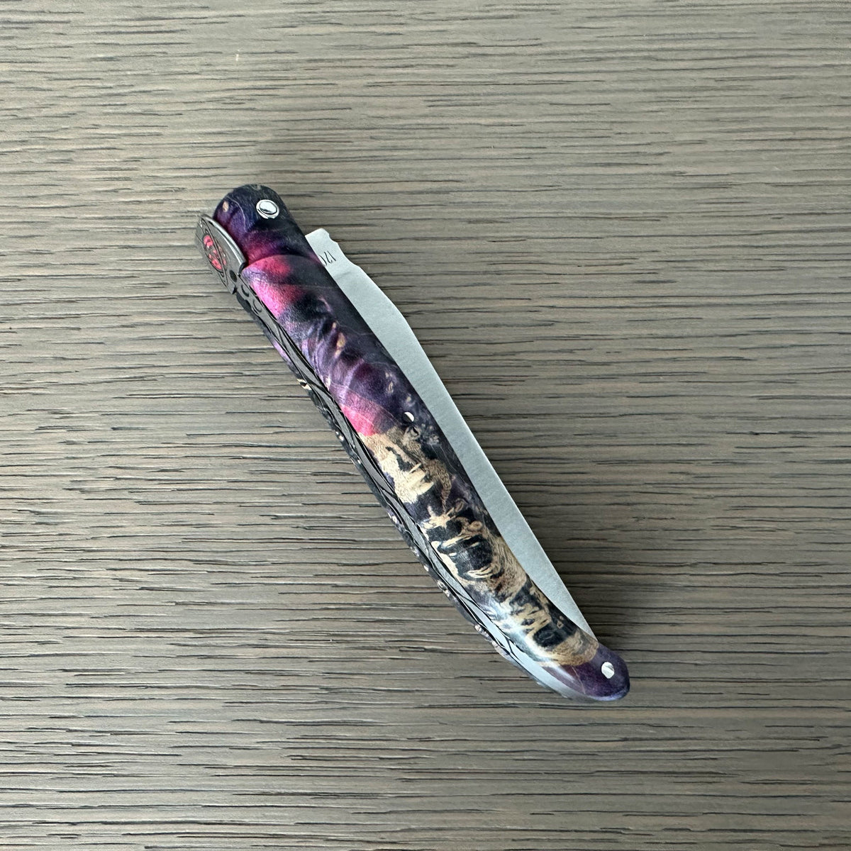 Closed knife showing magenta and pale burl in the handle