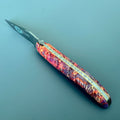 Laguiole Cosmos Space Bee knife with bright fire elder burl handle on a blue background
