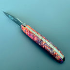 Laguiole Cosmos Space Bee knife with bright fire elder burl handle on a blue background