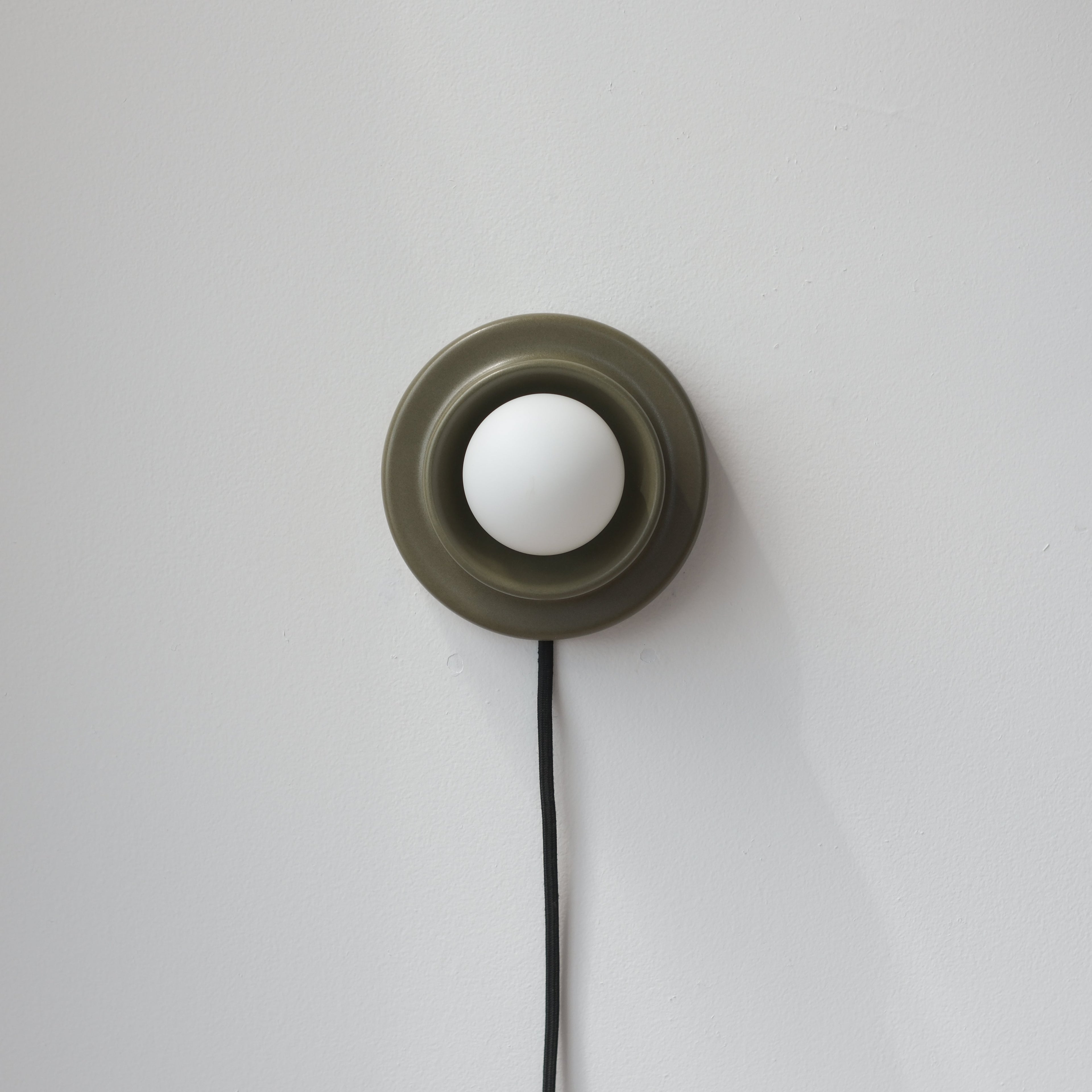 Q Sconce in Dune glaze lit at night