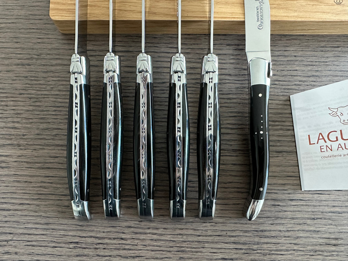 Row of steak knives standing on end next to the Laguiole en Aubrac booklet