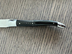 Close view of a black horn handle with steel pins and polished bolster