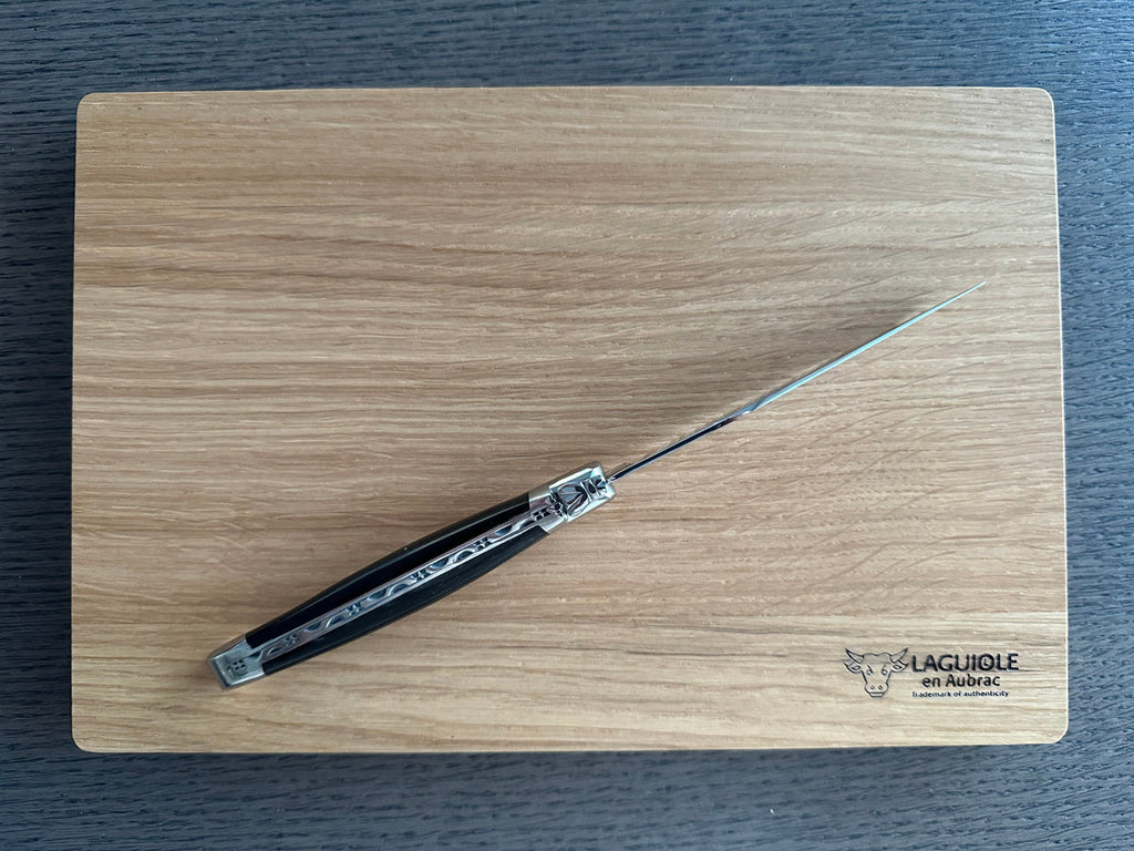 One steak knife lying diagonally on the engraved wooden box