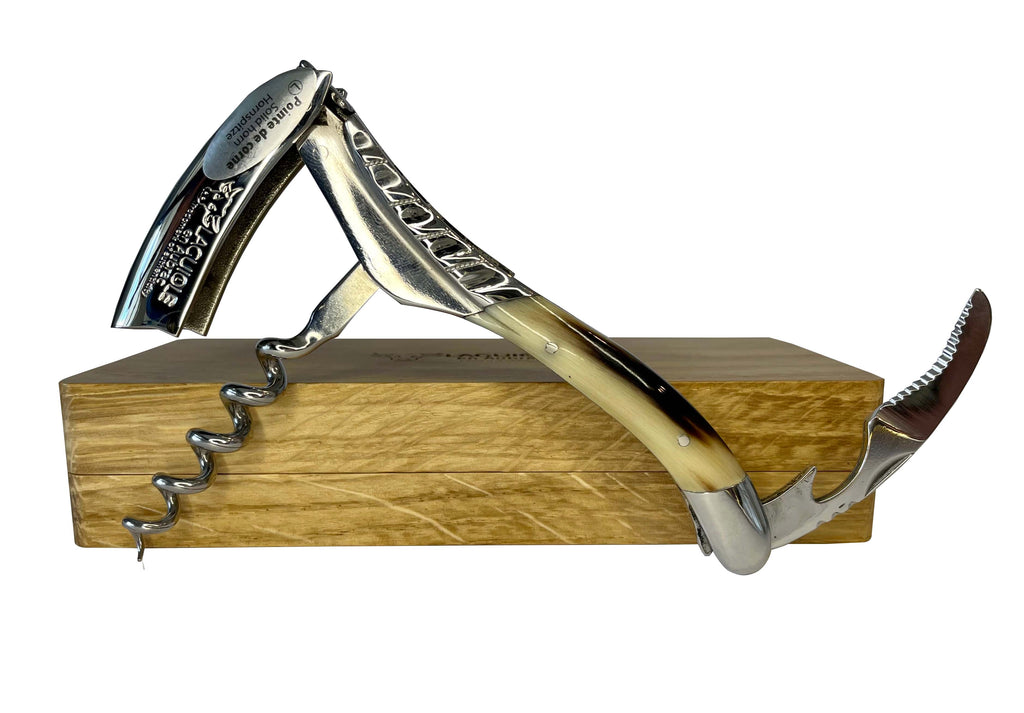 Opened corkscrew standing on the edge of the oak box