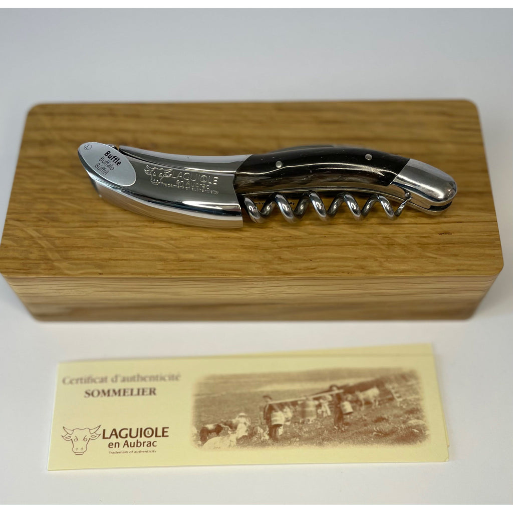 Dark horn corkscrew lying on its oak box above the certificate of authenticity