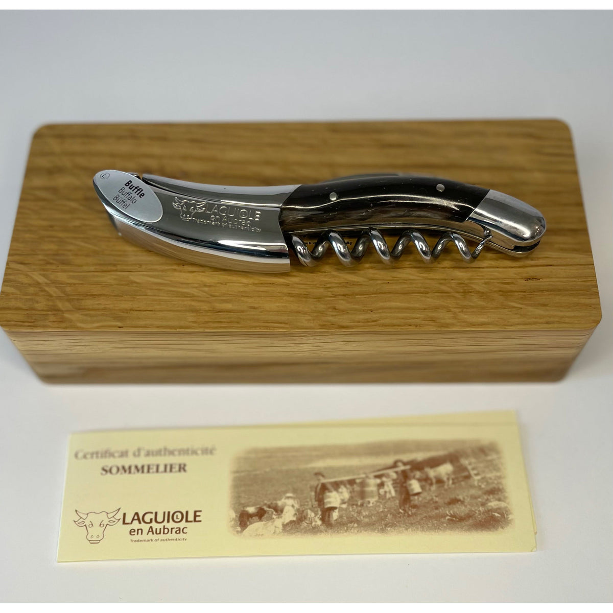 Dark horn corkscrew lying on its oak box above the certificate of authenticity