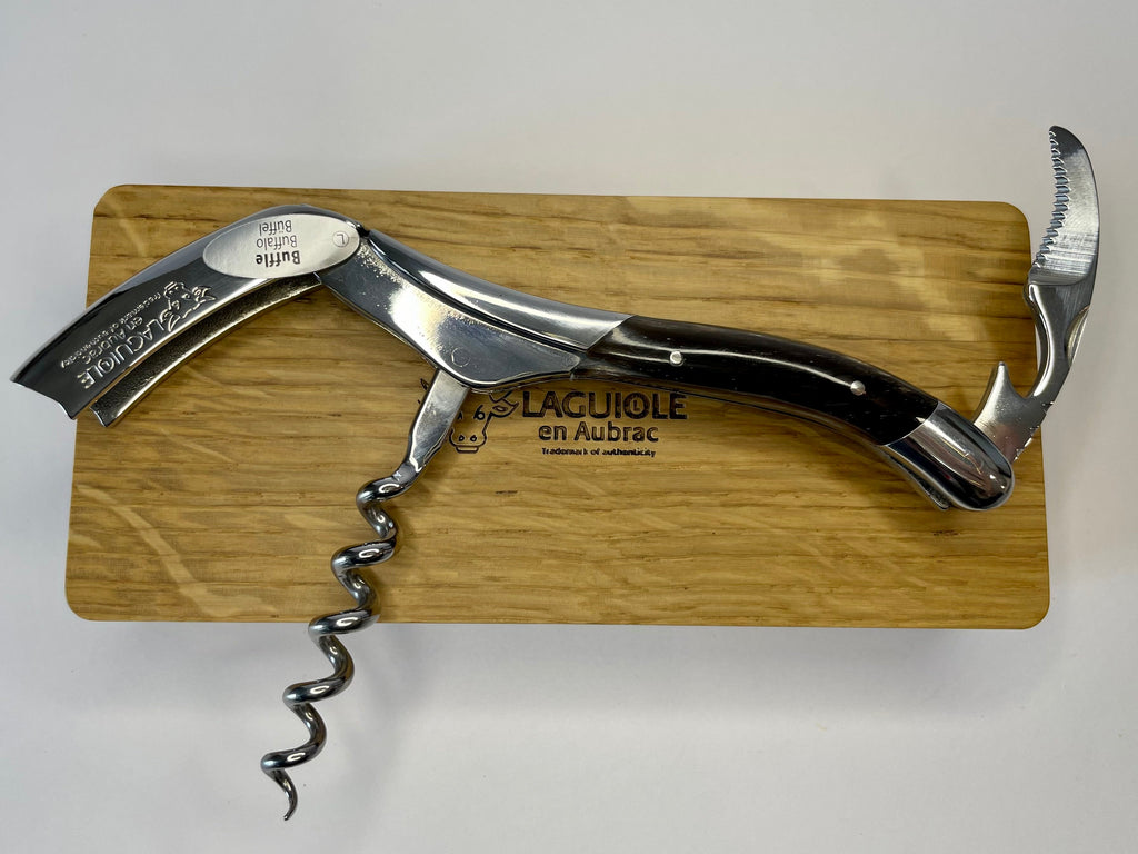 Opened corkscrew laid across the oak box with the foil cutter up