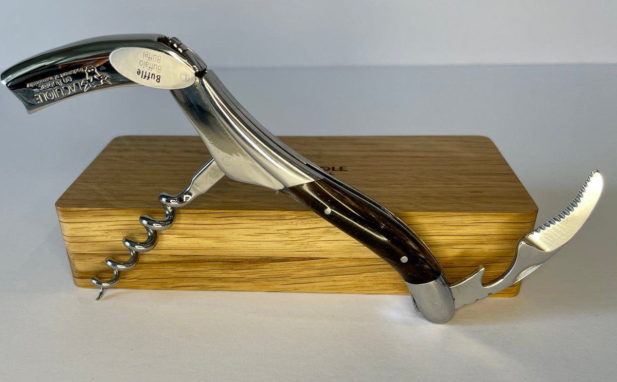 Opened corkscrew standing on the edge of the oak box