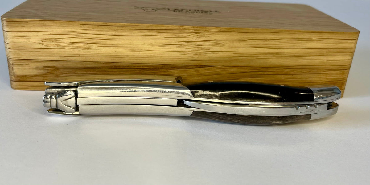 Folded corkscrew lying in front of the closed oak box