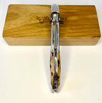 Folded corkscrew standing upright against the oak box, spine facing out