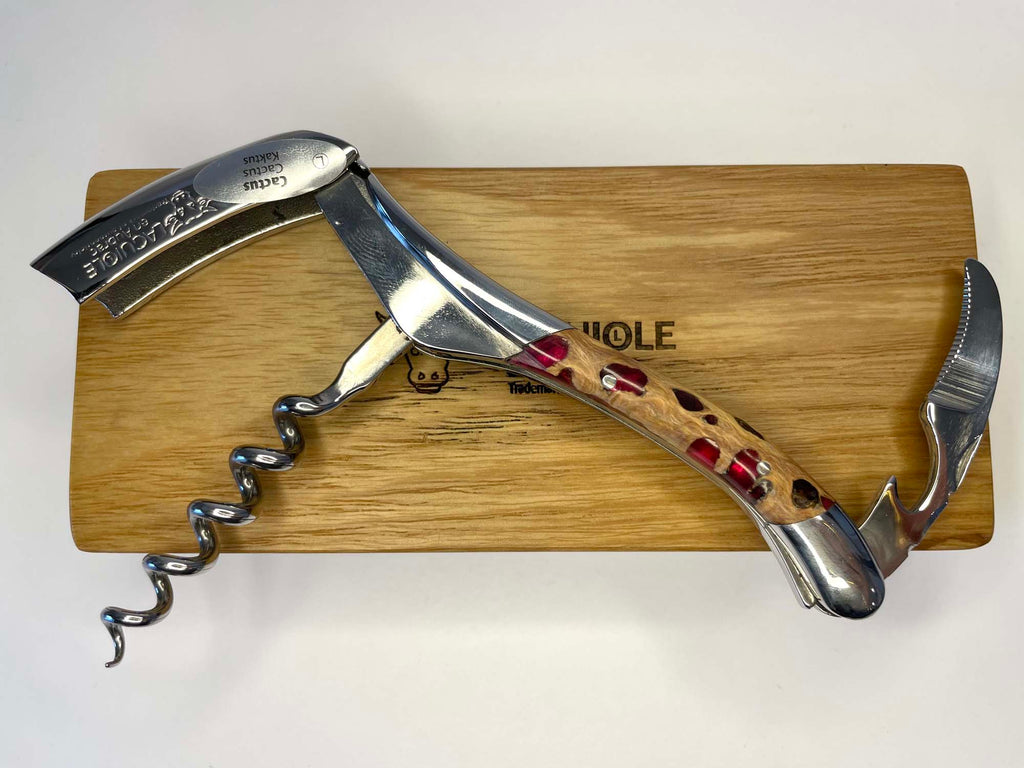 Opened corkscrew laid across the oak box with the foil cutter lifted