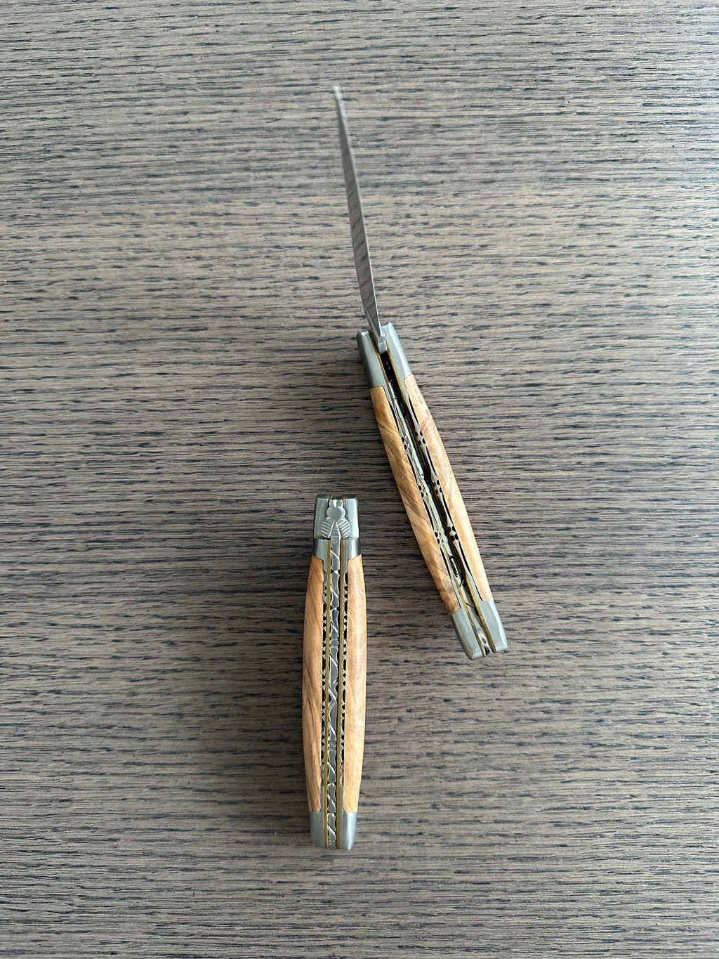 Two views of the olive wood knife on a pale wood surface